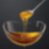 Golden honey dripping from a spoon into warm water